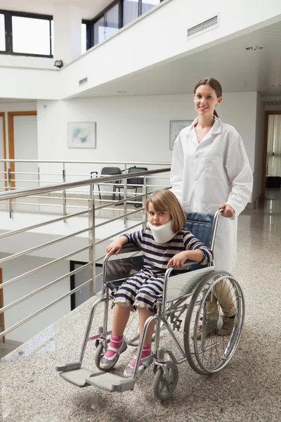 Child in neck brace being pushed in wheelchair by doctor — Stock Photo #23050014