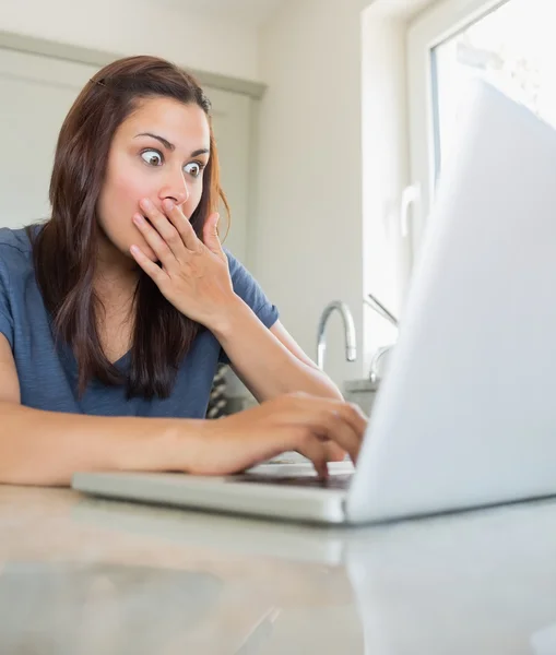 Woman looking surprised while using the laptop