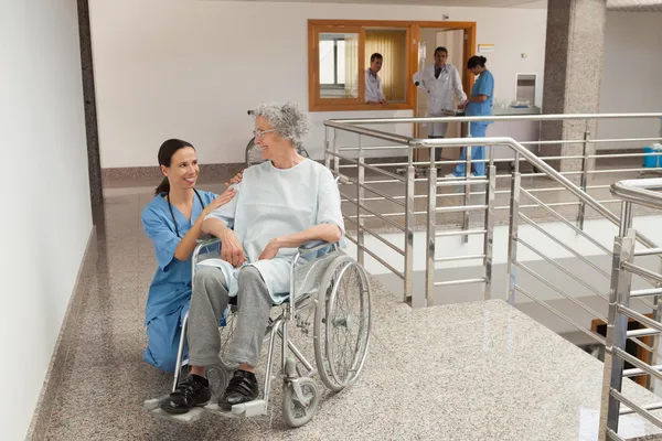 Nurse kneeling beside old women sitting in wheelchair