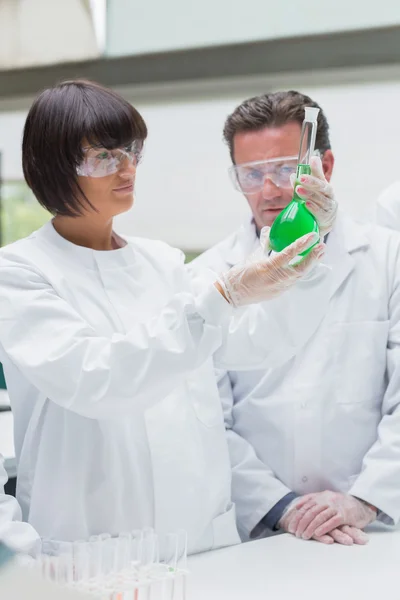 Chemists viewing green liquid