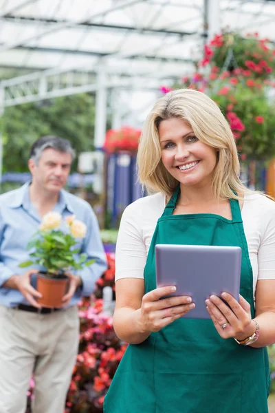 Cheerful florist holding a tablet pc in garden center — Stock Photo #23088270