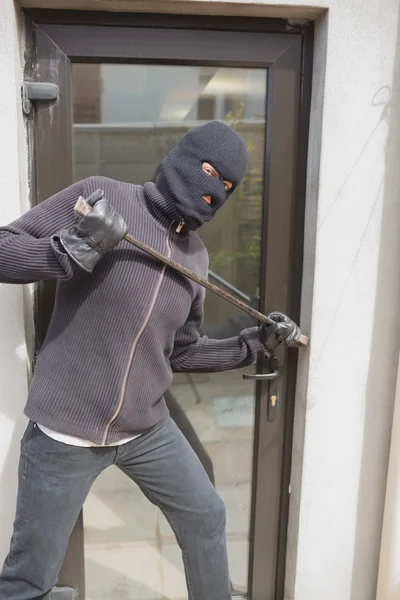 Burglar breaking into home using crow bar