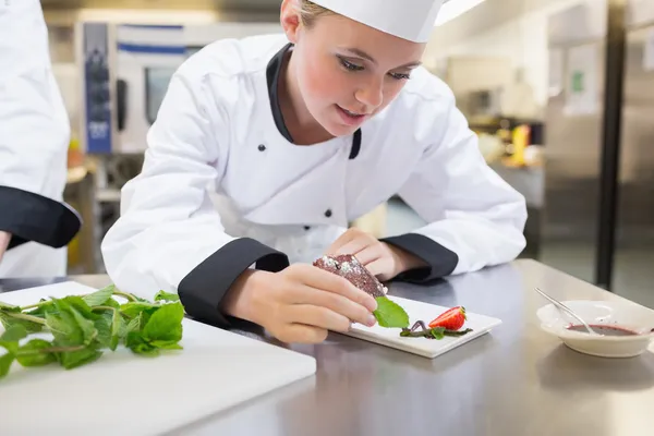 Chef putting mint on dessert plate