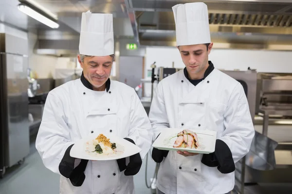 Two Chef\'s looking down at their dishes