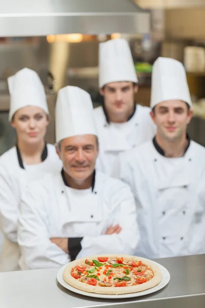 Pizza on the counter with team of Chef\'s behind