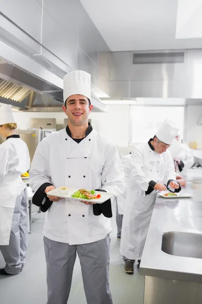 Happy chef holding a salmon dish