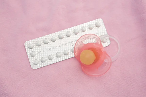 Contraceptive pill packet with pink soother — Stock Photo #24062347