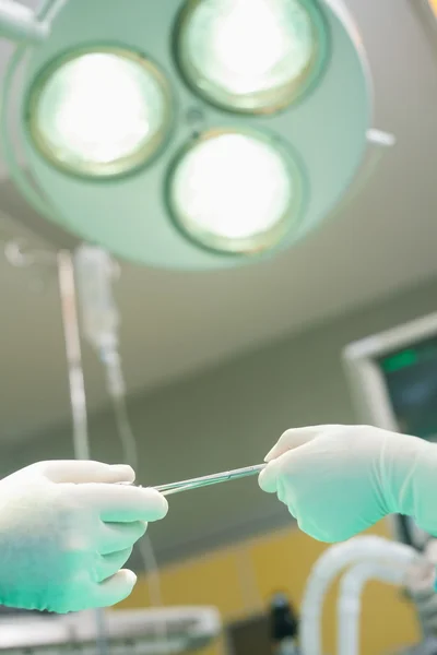 Nurse giving surgical scissor during an operation