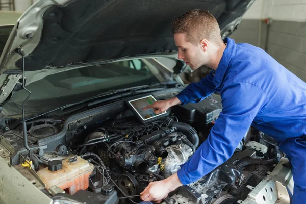 Mechanic with digital tablet repairing car engine