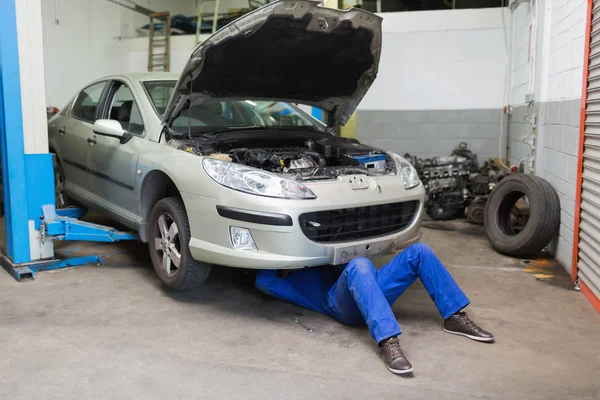 Male mechanic working under car