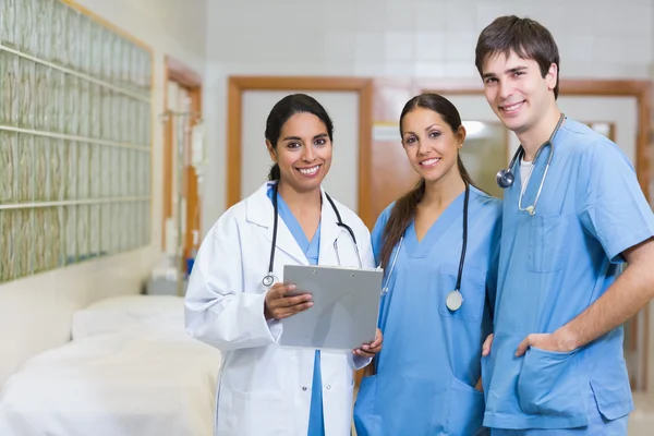 Smiling doctor and smiling male and female nurse in a hallway