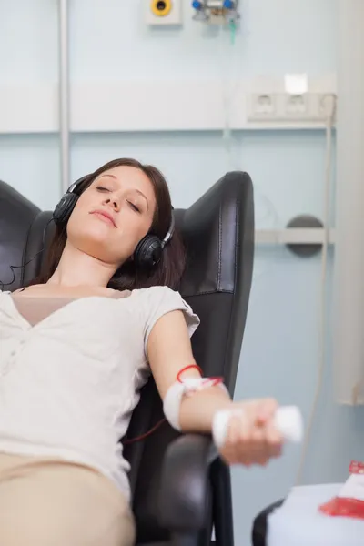 Female patient listening to music while giving her blood in a ho