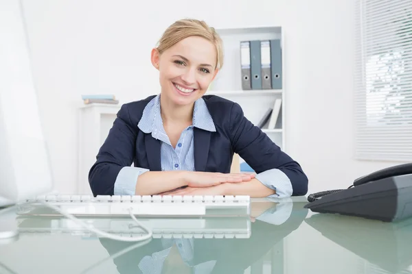 Smiling confident business woman with computer at desk