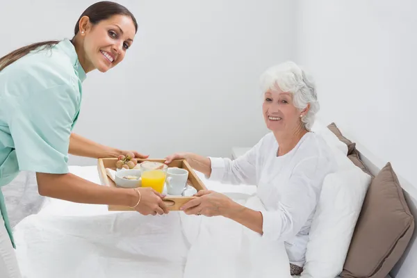 Home nurse giving a breakfast to the old woman