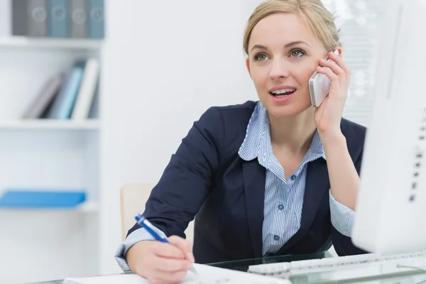 Business woman writing while on call at office