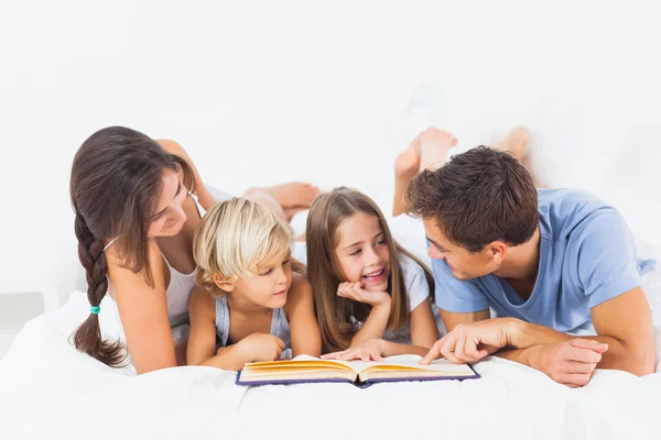 Family reading book on the bed