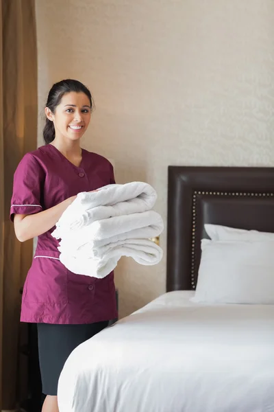 Smiling hotel maid holding towels