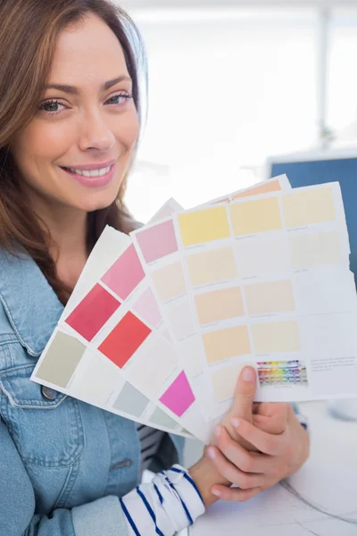 Cheerful interior designer holding up colour samples