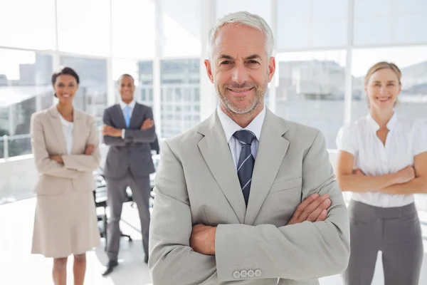 Businessman with arms folded standing in front of colleagues
