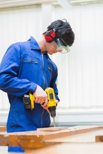 Student of a woodworking class drilling a hole