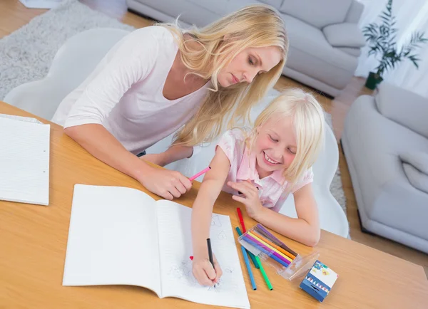 Mother and daughter drawing together at table