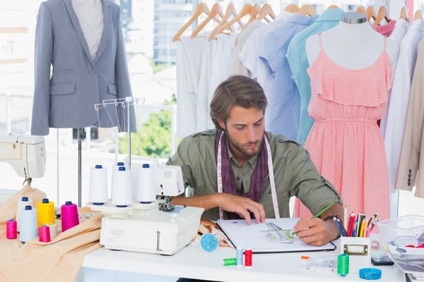 Handsome fashion designer drawing with pencils