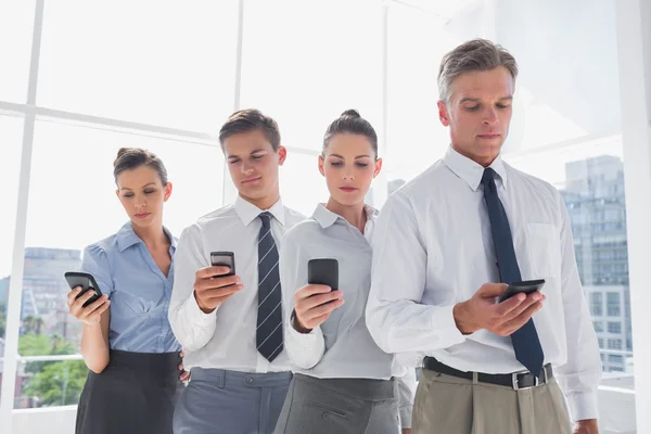 Team of business standing together in line with their mobile