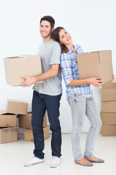 Husband and wife carrying boxes in their new house