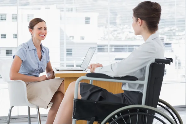 Businesswoman speaking with disabled colleague