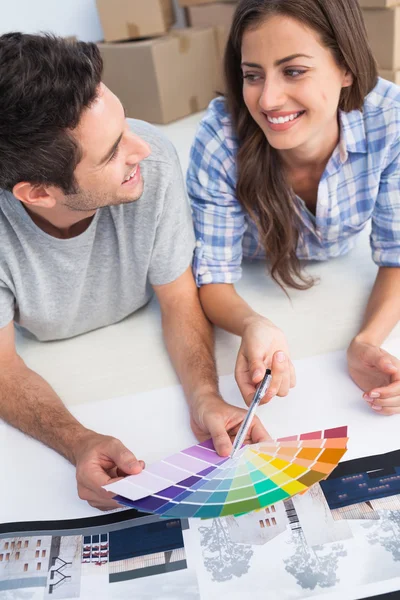 Happy couple looking at a color chart to decorate their house