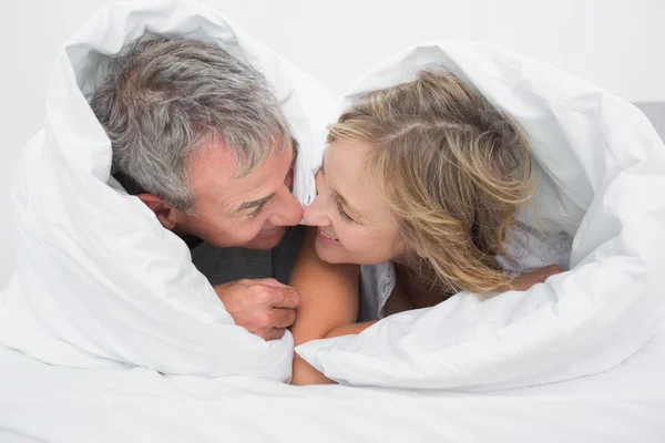 Loving middle aged couple under the duvet