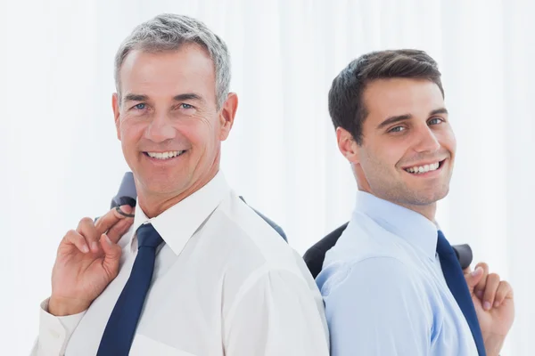 Smiling businessmen posing back to back together while holding t