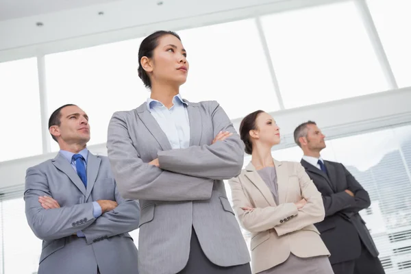 Unsmiling work team posing crossing arms