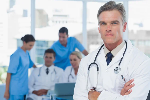 Experienced doctor posing with colleagues in background