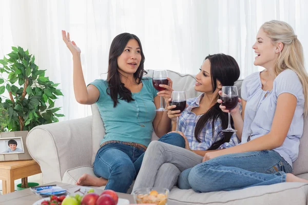 Cheerful friends having red wine together and talking