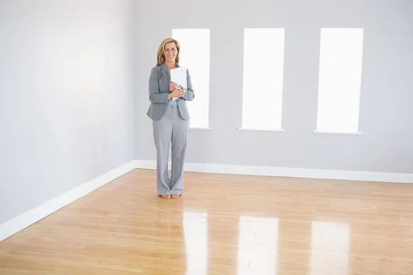 Joyful realtor standing in a room holding documents