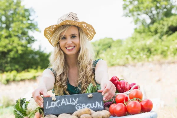 Happy young female farmer standing at her stall