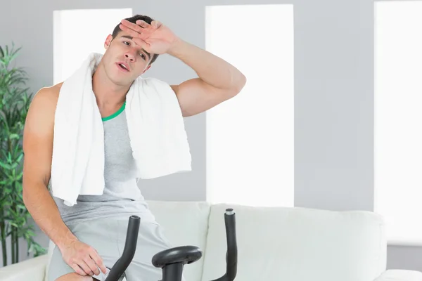 Exhausted handsome man exercising on exercise bike