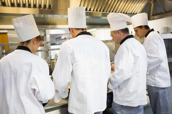 Four chefs working in industrial kitchen