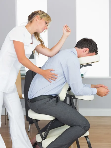 Masseuse treating clients back with elbow in massage chair — Stock Photo #33441659