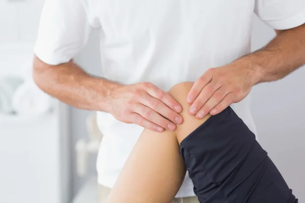 Physiotherapist checking knee of a patient