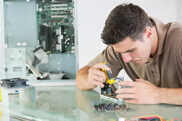 Handsome serious computer engineer repairing hardware with pliers