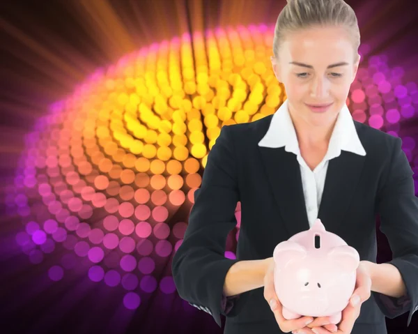 Blonde businesswoman holding piggy bank