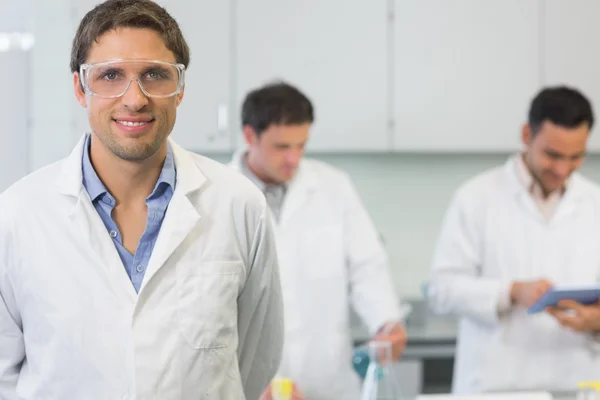 Smiling scientist with colleagues at work in the lab