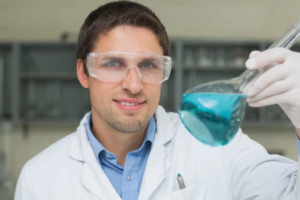 Male researcher holding flask with blue liquid in the lab