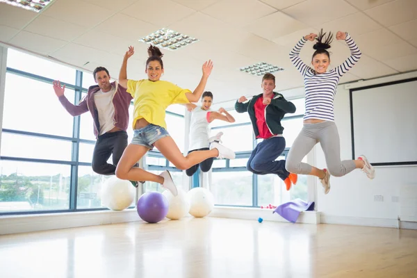 Fit people jumping in bright exercise room