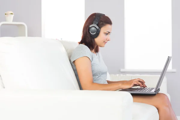 Attractive woman using her notebook and listening to music