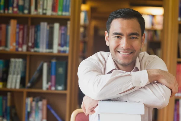 Cheerful attractive man posing leaning on a stack of books