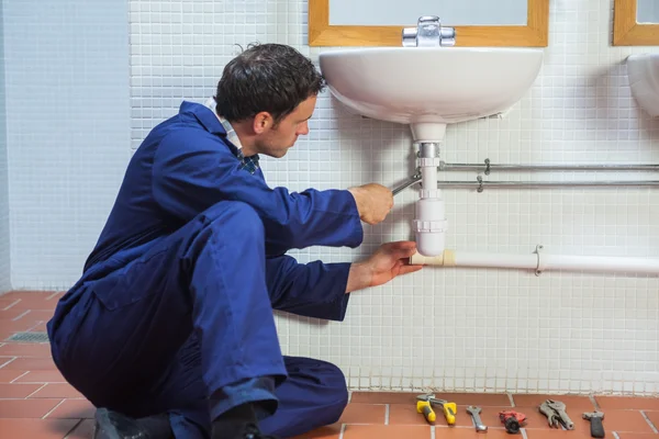 Handsome plumber repairing sink