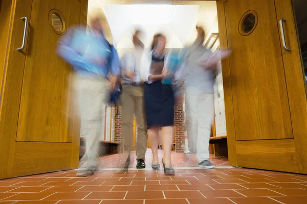 Group of blurred people walking through open doors